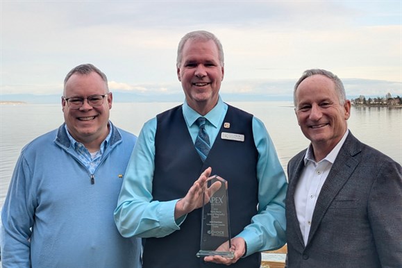 A charming white gazebo with a conical roof sits along a scenic, fenced pathway by the waterfront